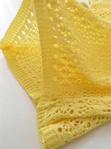 Close-up of bright yellow crochet knit top featuring intricate hollow geometric patterns
