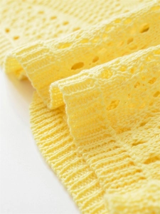 Close-up of bright yellow crochet knit top with intricate hollow-out floral patterns