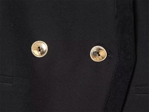 Detail of premium black twill jacket with ornate gold buttons and precise pocket stitching