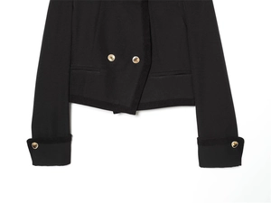 Detail of short black jacket featuring golden double-breasted buttons and woven texture