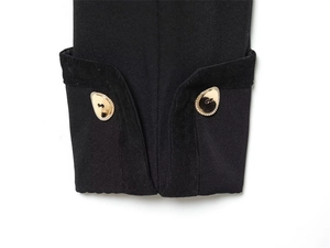 Close-up of black jacket cuff with corduroy patch and golden logo metal buttons