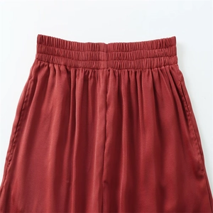 Détail de la taille élastique sur le pantalon fluide en soie rouge foncé à jambes larges