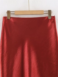 Detail of the elegant red satin skirt with high luster fabric and smooth minimalist waistband