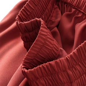 Gros plan de la taille élastique large et de la texture du tissu du pantalon rouge rouille