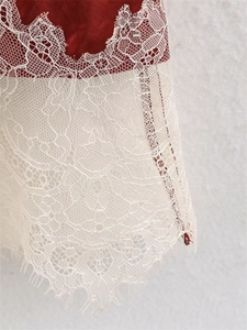 Detailed close-up of red satin skirt featuring intricate white floral eyelash lace trim