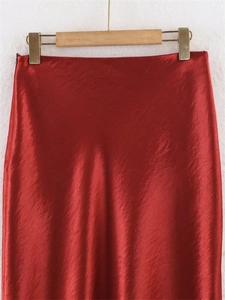 Detailed view of the smooth red satin fabric texture on a minimalist midi skirt