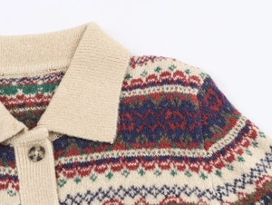 Detailaufnahme des Fair-Isle-Strickmusters und Knopfes am beigen Polo-Strickpullover