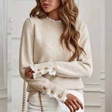 Detail of knitted cardigan with lace trim collar and golden buttons on the sleeve cuffs