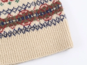 Detailaufnahme des Fair-Isle-Jacquardmusters und des Rippensaums am beigen Strickcardigan