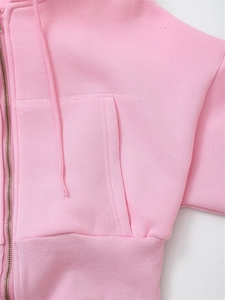 Detail of pink cropped hoodie showing metal zipper and ribbed hem texture