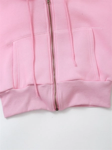 Detail of pink zip-up hoodie featuring a vintage bronze zipper and ribbed hem