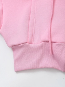 Detail of pink hoodie featuring ribbed hem stitching and woven drawstring texture
