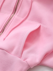 Detail view of pink cropped zip-up hoodie featuring metal zipper and ribbed hem texture