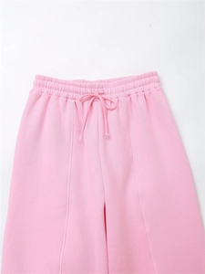 Detail of pink joggers featuring elastic waistband with drawstring and vertical seam