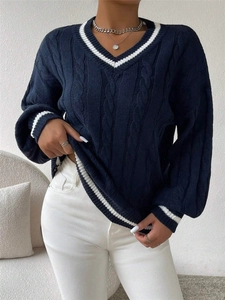 Detail of cable knit texture and contrasting white stripes on a V-neck navy sweater