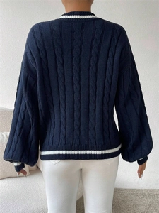 Detail view of the cable-knit pattern and white stripes on the back of navy blue sweater