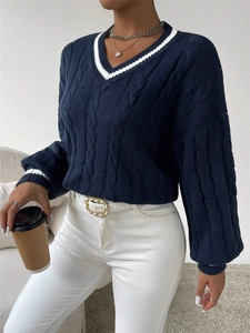 Detail view of navy blue cable-knit sweater featuring white striped V-neck and cuffs