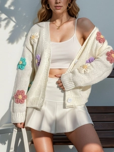 Détail d'un gilet en tricot blanc orné de fleurs colorées en crochet 3D
