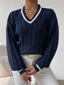 Detail of V-neck cable knit sweater featuring navy blue fabric with white contrast stripes