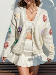 Détail d'un cardigan blanc à col en V avec des décorations de fleurs colorées en crochet 3D