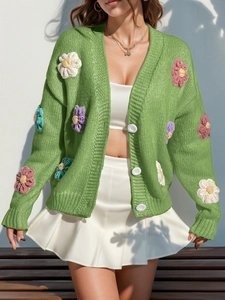 Détail du cardigan vert herbe avec des appliques de fleurs crochetées en 3D colorées