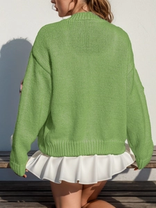 Détail du cardigan vert en tricot avec ourlet à volants blancs et texture au soleil