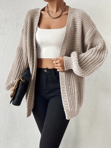 Detail of loose beige knit cardigan featuring chunky texture and lantern sleeves style