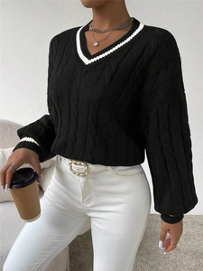 Detail of V-neck cable-knit sweater with white striped edges and black textured fabric