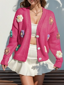 Détail du cardigan en maille rose avec fleurs au crochet 3D et grands boutons blancs