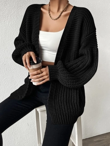 Close-up of black chunky knit cardigan with oversized shoulder design and ribbed cuffs