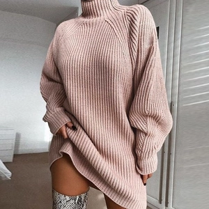 Close-up of pink oversized turtleneck knit dress with ribbed texture and long sleeves