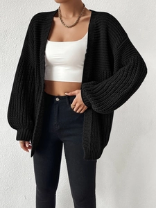 Close-up of black chunky knit cardigan featuring oversized balloon sleeves and thick texture
