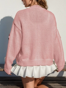 Détail du pull en maille rose avec poignets côtelés et ourlet blanc superposé à volants
