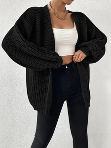 Detail of chunky knit black cardigan showing textured vertical stripes and oversized fit