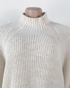 Detailed view of the mock neck and chunky knit texture on this cream-white raglan sweater