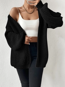 Detail of loose black chunky knit cardigan with long sleeves and gold chain necklace