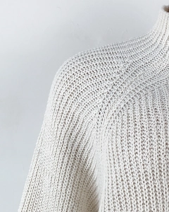 Close-up of cream white knit sweater showing ribbed turtleneck and soft shoulder texture