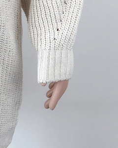 Close-up detail of cream knit sweater cuff showing textured ribbed knit craftsmanship
