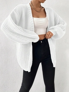 Close-up of chunky knit white cardigan showing texture, drop shoulders and cuffed sleeves