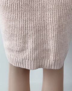 Detailed close-up of wide ribbed hem on a cozy pale pink chunky knit sweater dress