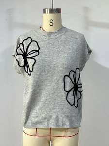 Grey knitted vest featuring large black 3D floral patterns and a classic round neck