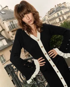 Détail de poignets évasés avec volants plissés blancs et boutons dorés sur une robe en maille