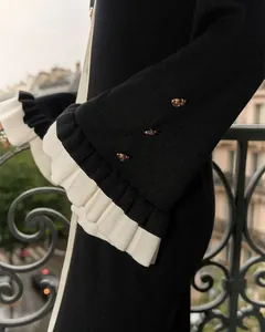 Détail de la manche en maille avec poignets à volants blancs et boutons dorés