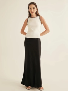 Women's minimalist white sleeveless knit tank top with black trim and black maxi skirt
