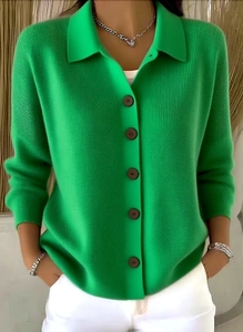 Detail der hellgrünen Strickjacke mit Polokragen und dunkelbraunen Knöpfen auf Stoff
