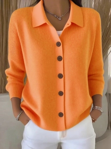 Detail of orange knit cardigan showing the polo collar, texture, and dark brown buttons
