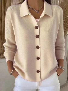Detailed view of beige knit cardigan featuring polo collar and dark contrast buttons