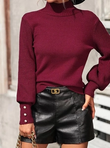 Detail of burgundy knit sweater showing lantern sleeves and elegant pearl buttons at the cuff