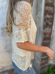 Detail of beige crochet knit cardigan showing intricate mesh hollow out design and flared sleeve