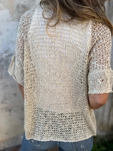 Close-up of beige hollow out crochet knit cardigan showing intricate mesh texture